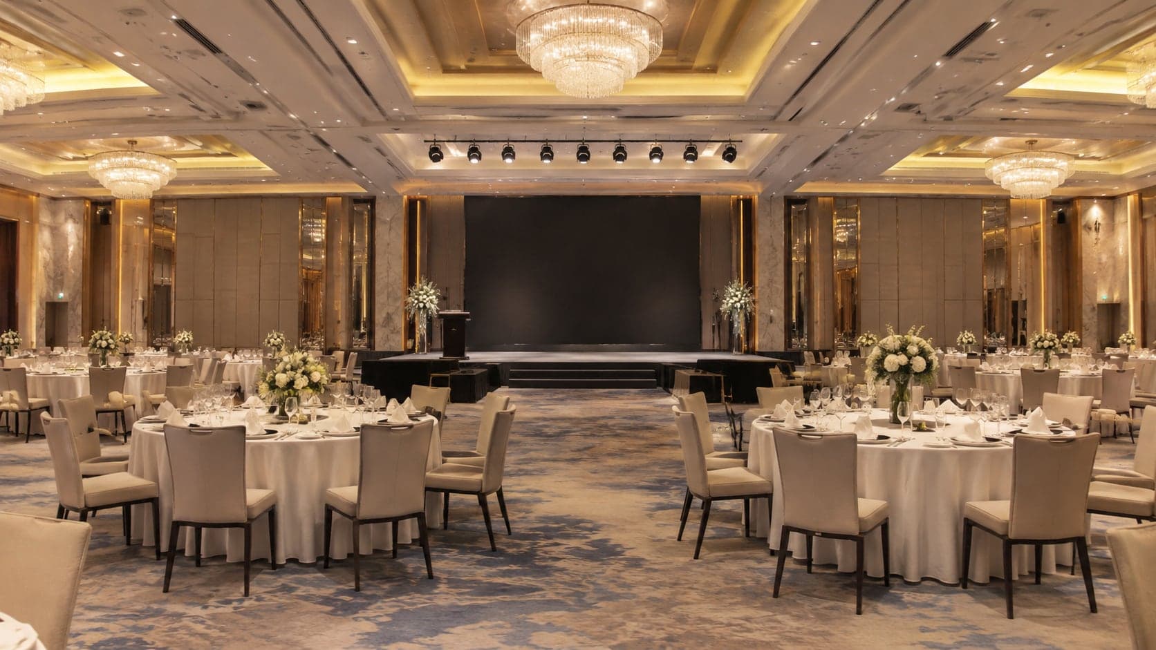 Hotel ballroom set banquet-style with round tables facing a stage