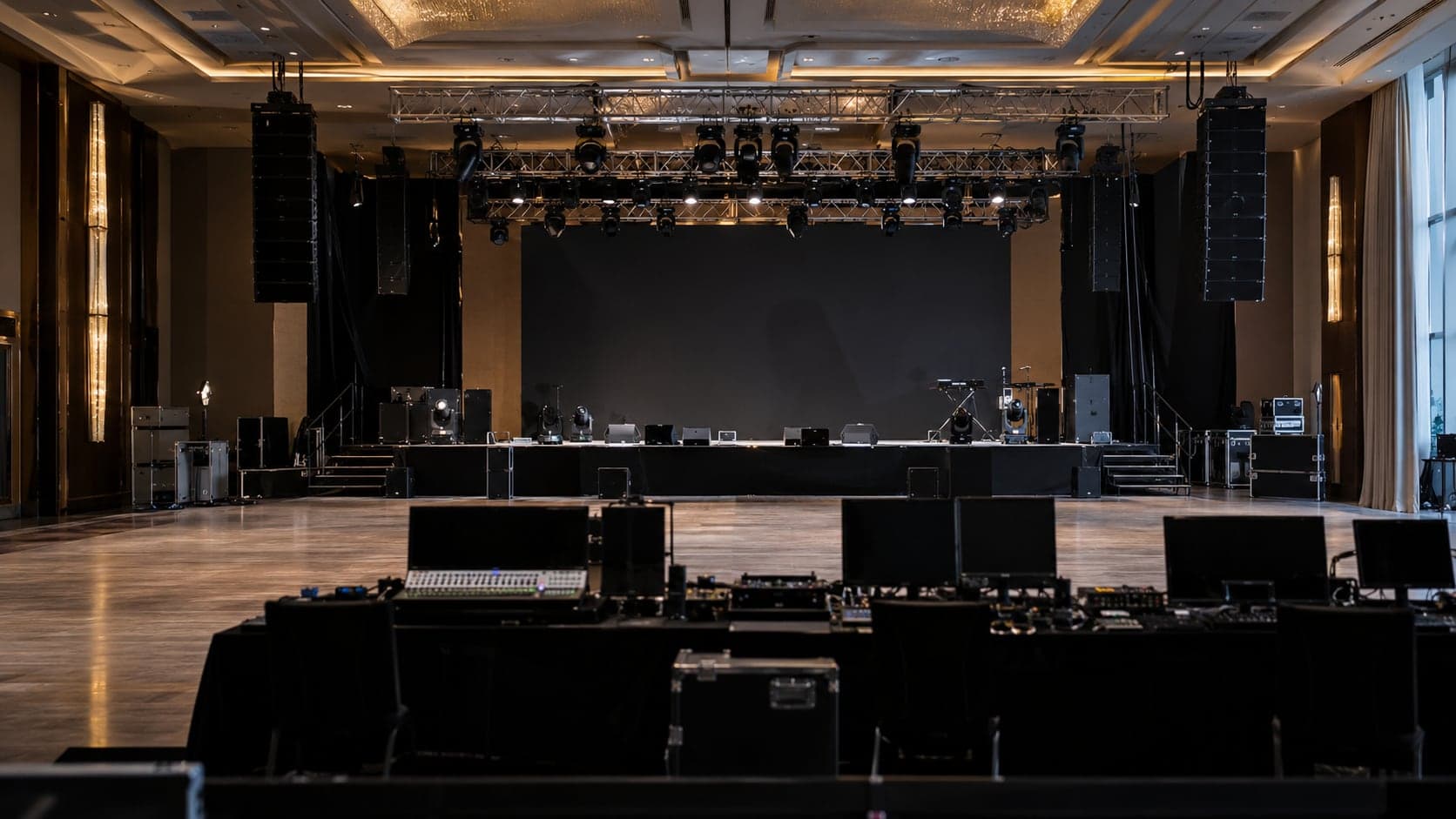Event stage with lighting truss, line-array speakers and front-of-house control desks
